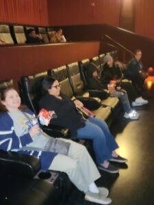 Adults and children seated in a movie theater with snacks.